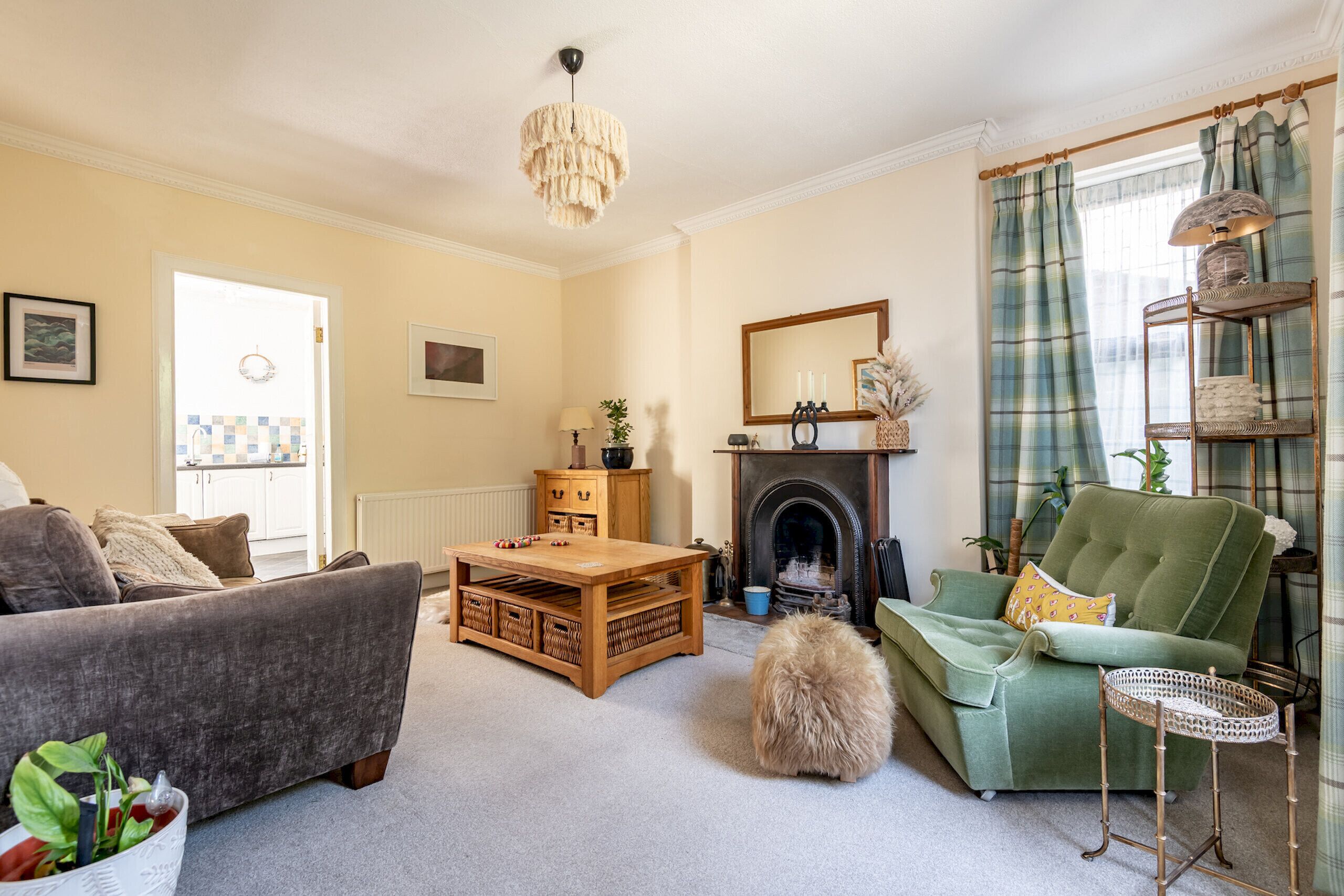 A cozy living room with a fireplace, a green sofa, a wooden coffee table, and a fluffy rug.