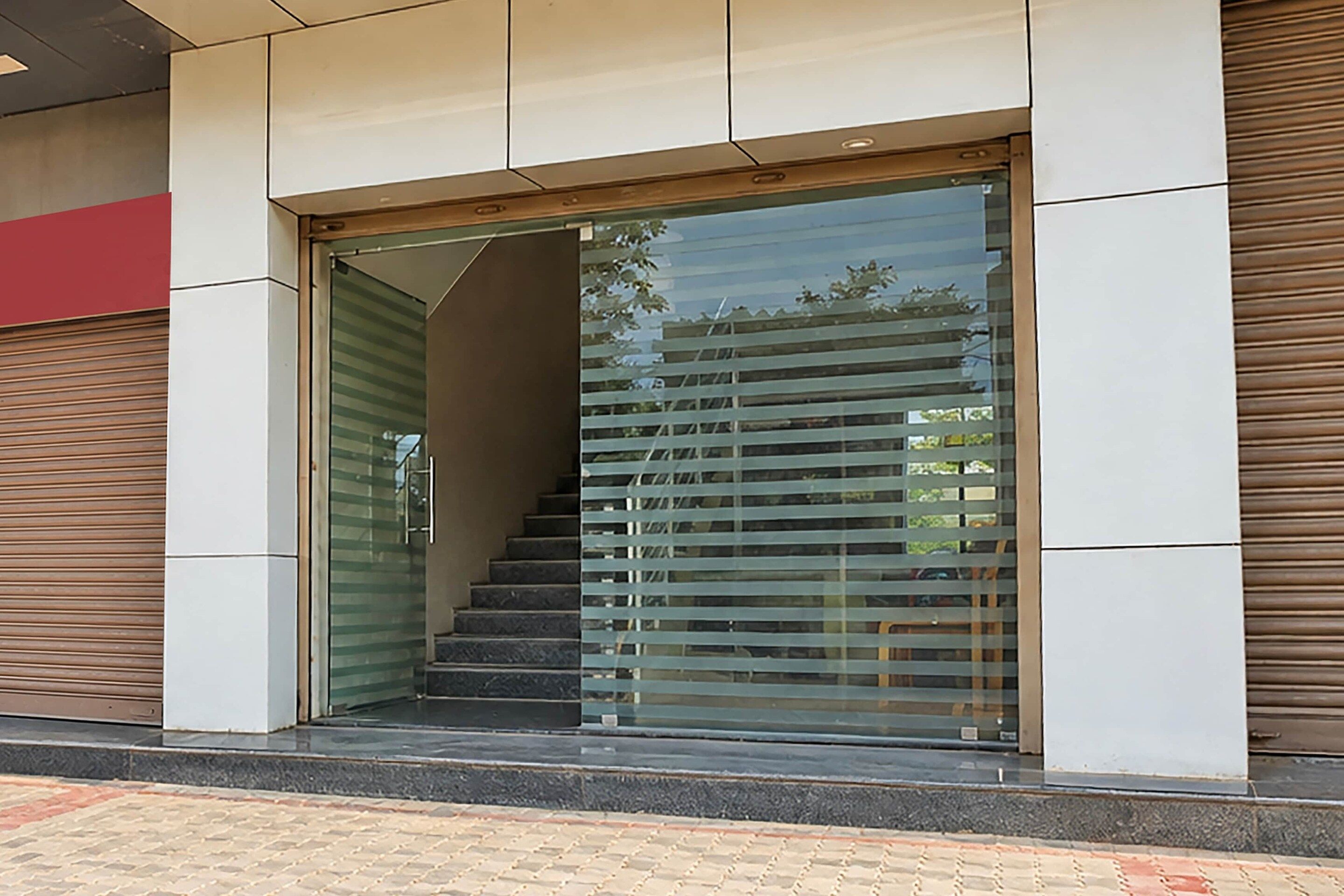 Entrada de un edificio con puerta de cristal y escalera que conduce al interior.