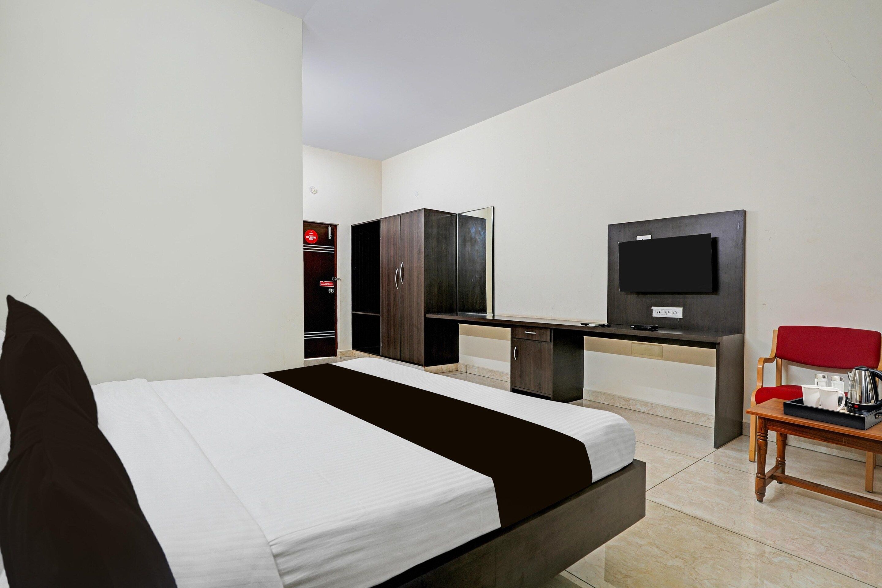 Una habitación de hotel con una cama, un escritorio, un televisor y una silla.