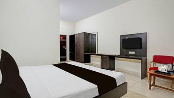 Una habitación de hotel con una cama, un escritorio, un televisor y una silla.