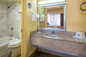 A bathroom with a marble-tiled wall, a bathtub, a sink with a mirror, and a towel rack. - Days Inn By Wyndham Hampton Near Coliseum Convention Center (Hampton)