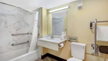 A bathroom with a bathtub, a sink, a toilet, and a mirror.