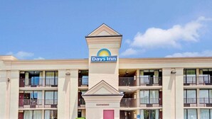 A Days Inn hotel with a central tower featuring the brand's logo, multiple balconies, and a registration sign. - Days Inn By Wyndham Hampton Near Coliseum Convention Center (Hampton)