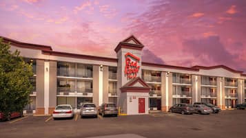 A Red Roof Inn with a parking lot and multiple cars parked in front.