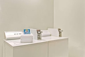 A hotel room with a white bed, a white desk, and a Snuggie box on the desk. - Days Inn By Wyndham Hampton Near Coliseum Convention Center (Hampton)