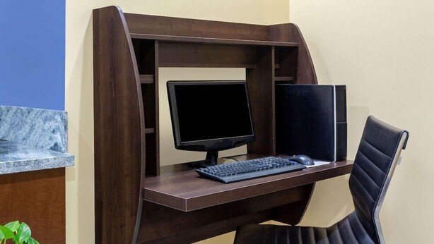 A wooden desk with a computer setup, including a monitor, keyboard, and mouse. - Days Inn By Wyndham Hampton Near Coliseum Convention Center (Hampton)
