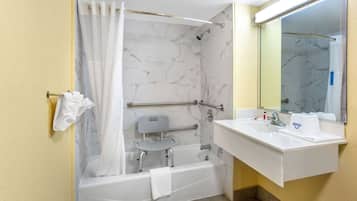 A bathroom with a bathtub, a shower, a vanity with a sink, and a mirror.