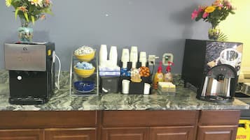 A coffee station with an espresso machine, cups, and condiments.
