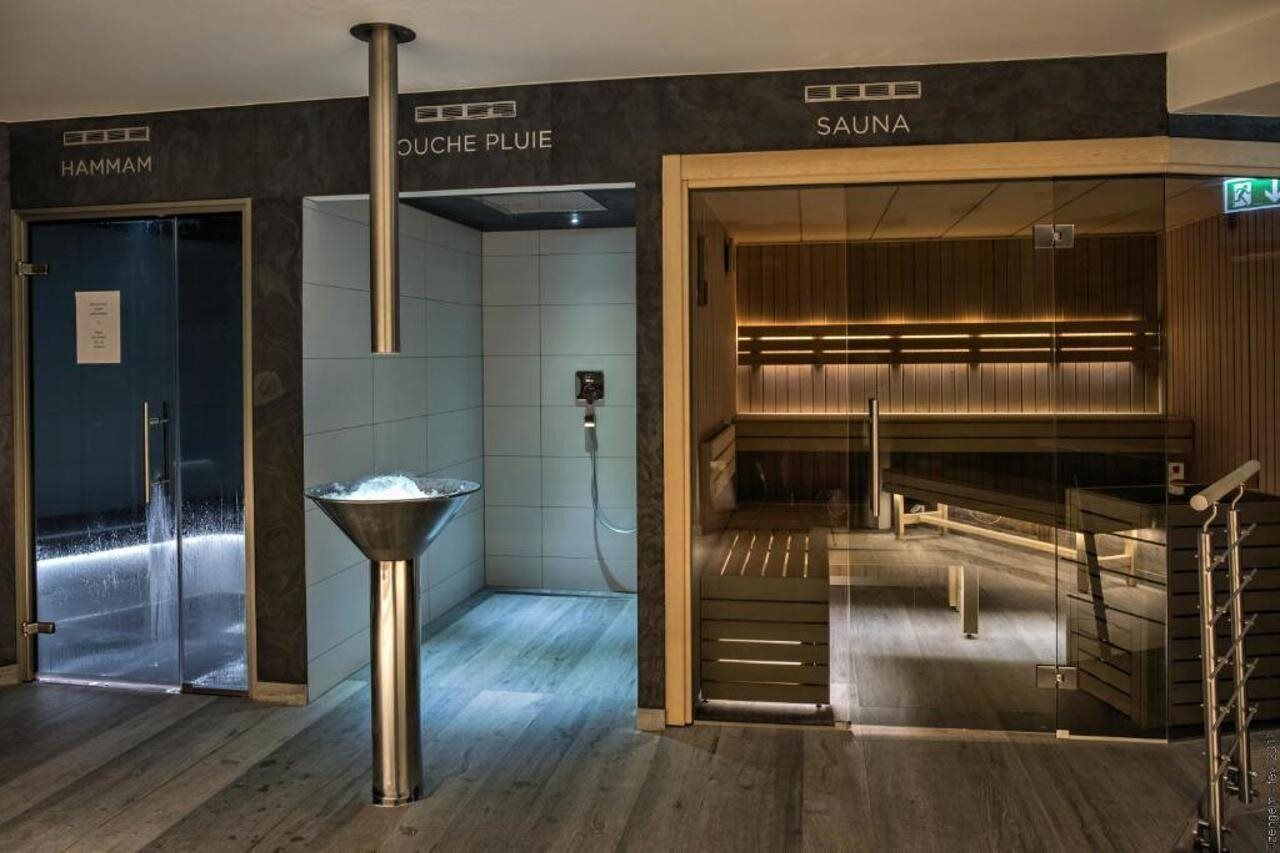 A sauna area with a wooden bench and a glass door leading to a steam room.