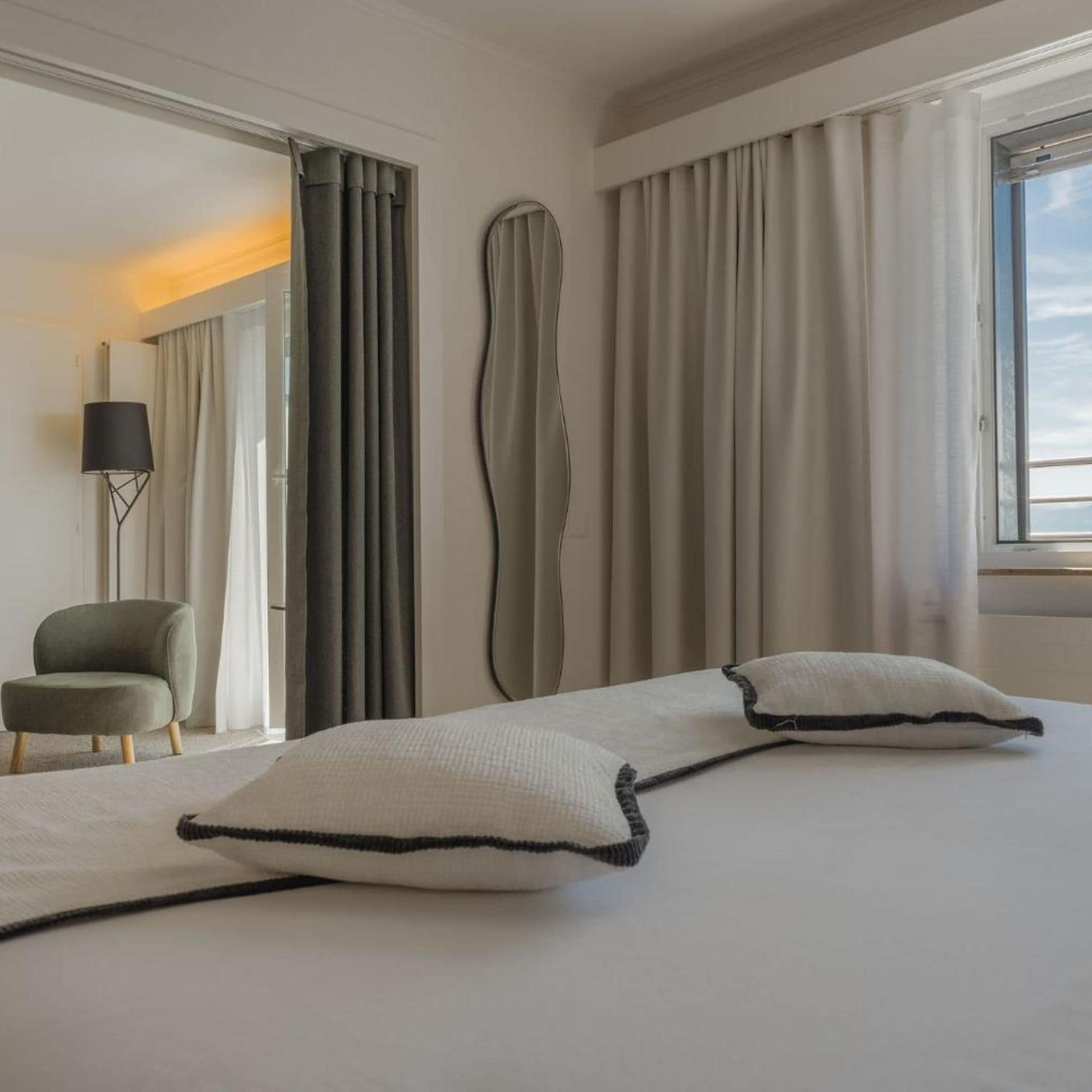 A hotel room with a bed, a chair, and curtains.