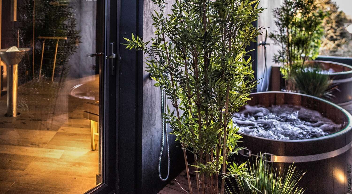 A modern bathroom with a glass door, a bamboo plant, and a heated floor.