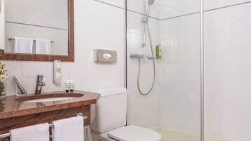 Een moderne badkamer met een douche met glazen wand, een toilet en een wastafel met spiegel erboven.