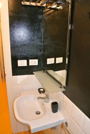 A bathroom with a white sink, a black countertop, and a mirror above it. - Vrbo Property (Milano)