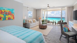 Habitación de hotel con cama, sofá, escritorio, silla y vista al océano.