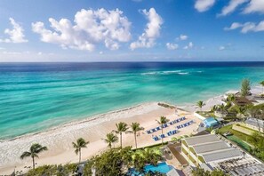 Ein Strandresort mit Swimmingpool, Liegestühlen und Palmen.