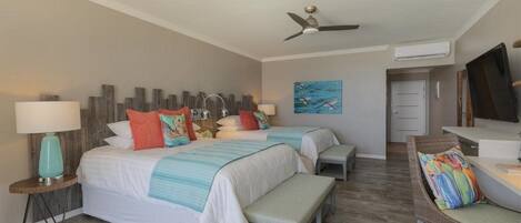 A bedroom with two beds, a ceiling fan, a TV, and a painting on the wall.