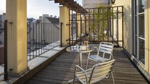 A balcony with a table and chairs, a small plant, and a view of the cityscape. - K+K Hotel Maria Theresia (Vienna)