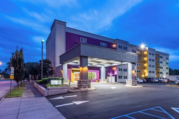 A multi-story hotel with a covered entrance, a parking lot, and a one-way street sign. - District 3 Hotel Ascend Hotel Collection (Chattanooga)