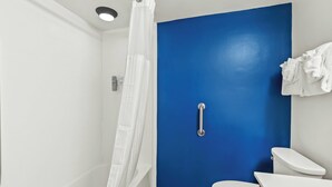 Une salle de bain avec une douche blanche, un mur bleu, des toilettes blanches et un porte-serviettes.
