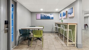 A modern office space with a meeting table, chairs, and a small bar area. - District 3 Hotel Ascend Hotel Collection (Chattanooga)