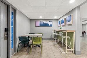 A modern office space with a meeting table, chairs, and a small bar area. - District 3 Hotel Ascend Hotel Collection (Chattanooga)