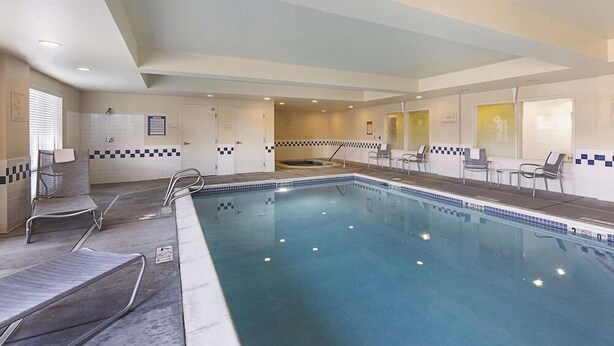Une piscine avec des chaises longues et un mur carrelé.