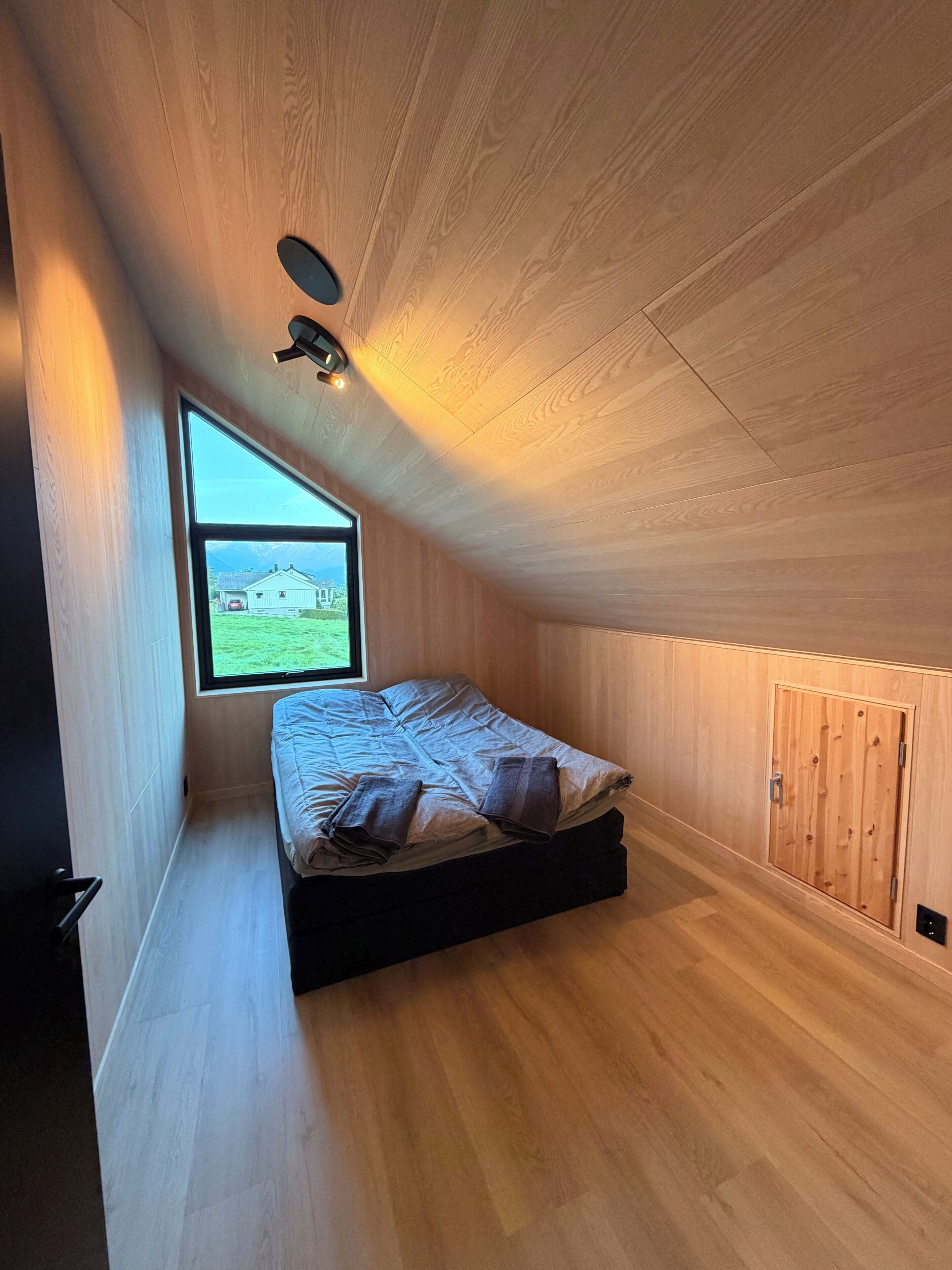 A room with a bed, a window, and a wooden ceiling.