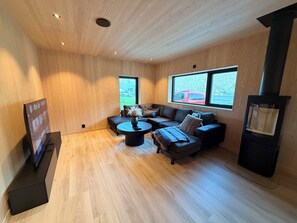 Ein modernes Wohnzimmer mit Ecksofa, rundem Couchtisch und Kamin.