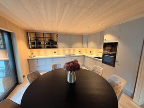 A modern kitchen with a central island, built-in appliances, and a dining area with a round table and chairs.