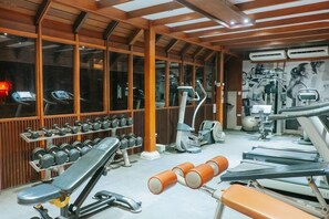 Uma academia com equipamentos de ginástica, racks de pesos e um espelho grande na parede.