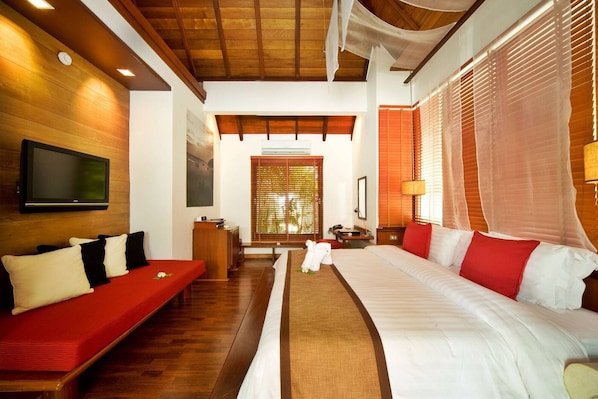Una habitación de hotel con cama, sofá, televisión, escritorio y ventana con persianas.