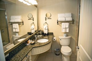 Une salle de bain avec deux lavabos, des toilettes, un miroir et des porte-serviettes.