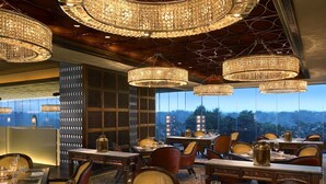 Un ristorante con diversi tavoli, lampadari e vista sulla città.