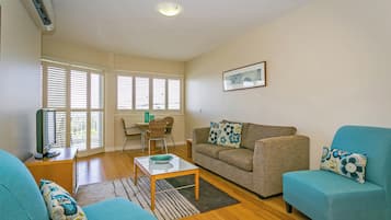 A living room with a sofa, a chair, a coffee table, and a television.