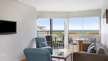 A modern living room with a TV, two sofas, a coffee table, and a balcony with a view.
