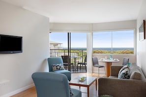 Ein modernes Wohnzimmer mit Fernseher, zwei Sofas, einem Couchtisch und einem Balkon mit Blick.