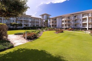 Un hotel de varios pisos con un césped cuidado y un cielo despejado.