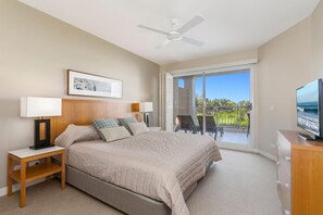 Un dormitorio con cama, mesitas de noche, televisión y un balcón con vistas.