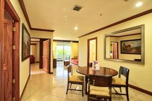 A hotel room with a dining area, a large window with curtains, and a framed picture on the wall. - Fiesta Resort All Inclusive Central Pacific - Costa Rica (El Roble)