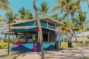 A colorful outdoor bar with a tropical theme, surrounded by palm trees. - Fiesta Resort All Inclusive Central Pacific - Costa Rica (El Roble)