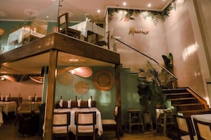 A dining area with tables, chairs, and a staircase leading to an upper level.