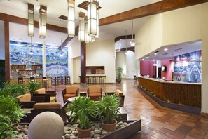 A hotel lobby with seating areas, a reception desk, and a mural on the wall. - Fiesta Resort All Inclusive Central Pacific - Costa Rica (El Roble)
