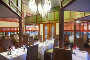 A restaurant interior with multiple dining tables, chairs, and a large chandelier. - Fiesta Resort All Inclusive Central Pacific - Costa Rica (El Roble)