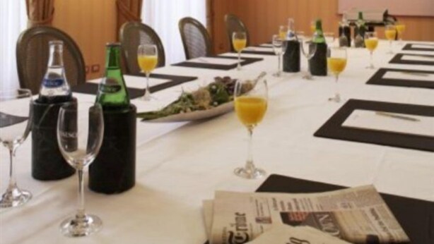 A conference room with a long table set for a meeting, equipped with microphones, glasses, and bottles. - Schweizerhof (Lucerne)