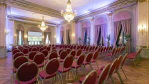 A formal room with rows of chairs, chandeliers, and arched windows. - Schweizerhof (Lucerne)