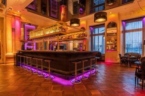 A bar area with a central bar, multiple stools, and a seating area with tables and chairs. - Schweizerhof (Lucerne)