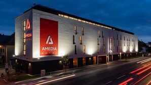 Un moderno edificio de hotel con un llamativo logotipo rojo y numerosas ventanas.