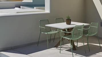 Um terraço no telhado com piscina, uma mesa com cadeiras e um vaso de planta.