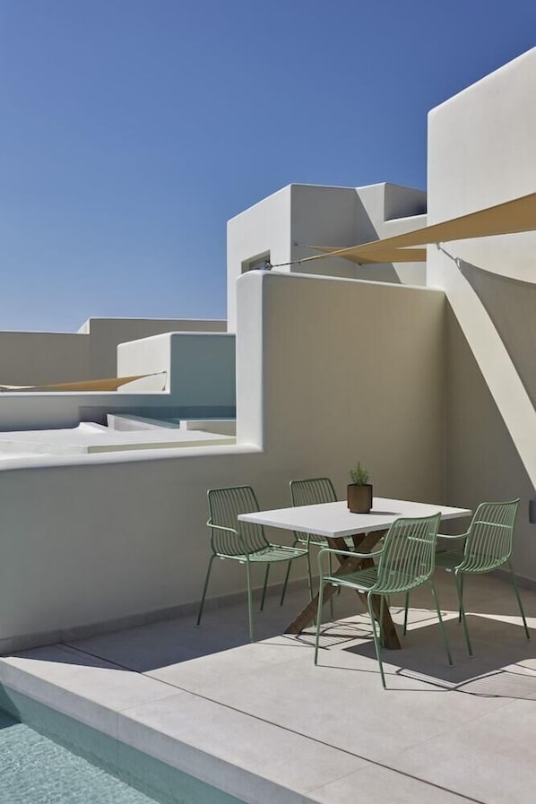 A rooftop terrace with a pool, a table with chairs, and a potted plant. - Apanemo Hotel and Suites (Santorini)