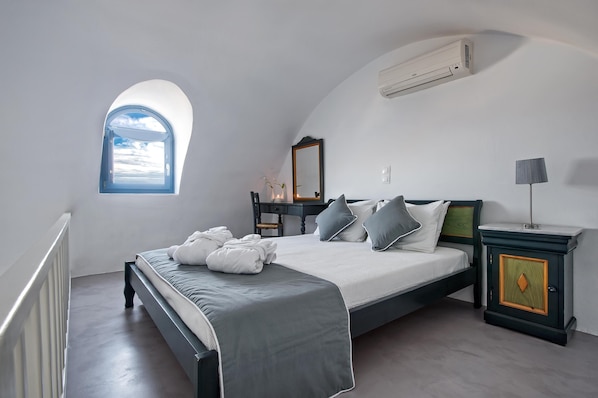 Ein Schlafzimmer mit Bett, Nachttisch, Kommode, Spiegel und Fenster mit Blick.